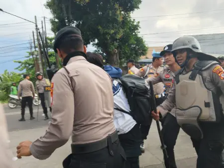 Demo di DPRD Jawa Barat Kembali Memanas, Polisi Tembakkan Gas Air Mata Petugas kepolisian mengamankan salah seorang peserta aksi di depan Mapolres Karawang, Jumat (29/8/2025).