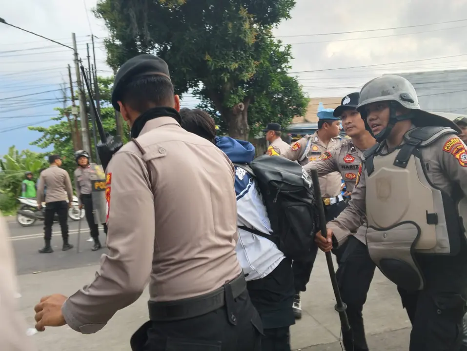 Petugas kepolisian mengamankan salah seorang peserta aksi di depan Mapolres Karawang, Jumat (29/8/2025).