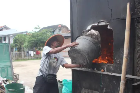 Seorang petugas Kebersihan sedang memasukan sampah di mesin Insenerator