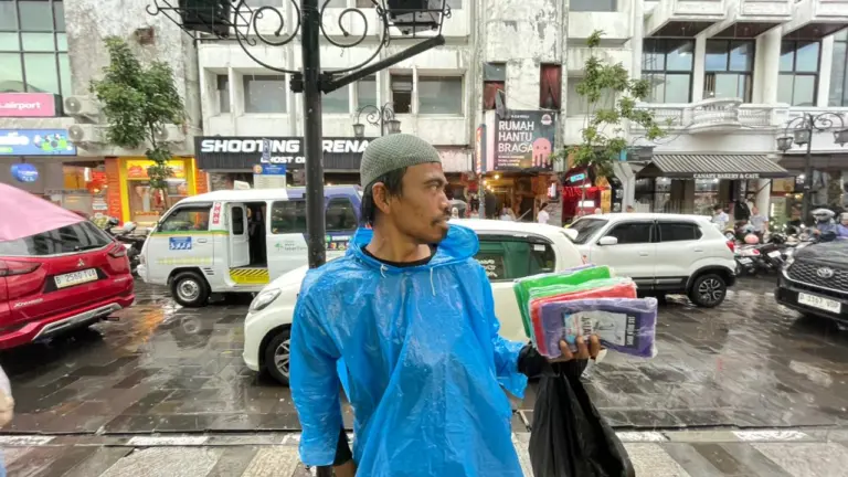 Di Tengah Hujan Bandung, Penjual Jas Hujan Bertahan dan Mengais Rezeki Penjual Jas Hujan di Braga Bandung (Sarah/Koran Mandala)
