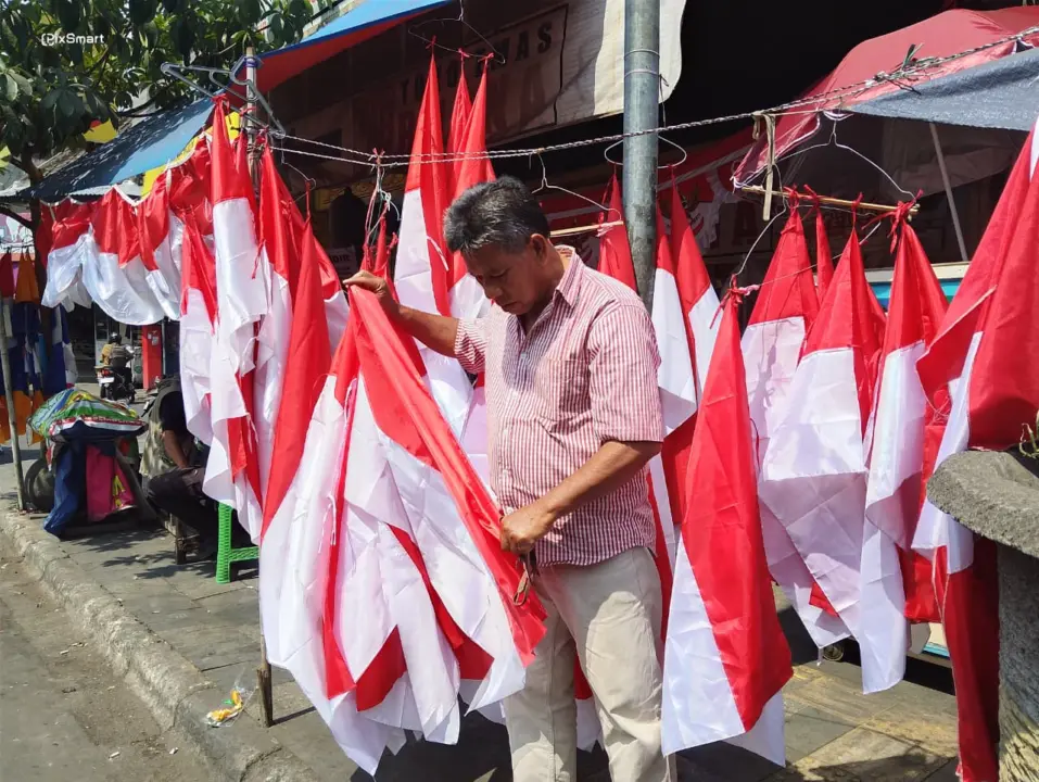 Pedagang musiman Komara maman menjajakan bendera Merah Putih jelang HUT ke-81 RI. (Sarah/Koran Mandala)