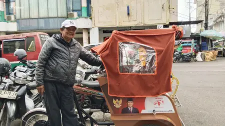 Becak Listrik Belum Dongkrak Penghasilan Tukang Becak Pasar Baru Penarik becak listrik Pepen Abidin (61) saat mangkal di kawasan Pasar Baru Kota Bandung, Selasa 22/9/2026 (Sarah/Koran Mandala)