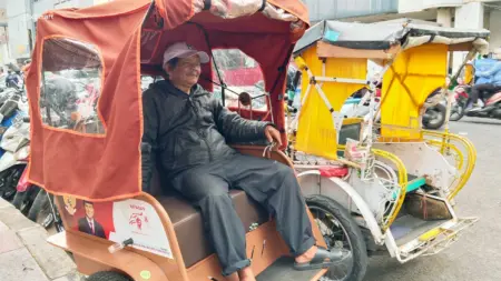 Pepen Ungkap Tantangan Menggunakan Becak Listrik Penarik becak listrik Pepen Abidin (61) saat mangkal di kawasan Pasar Baru Kota Bandung, Selasa 22/9/2026 (Sarah/Koran Mandala)